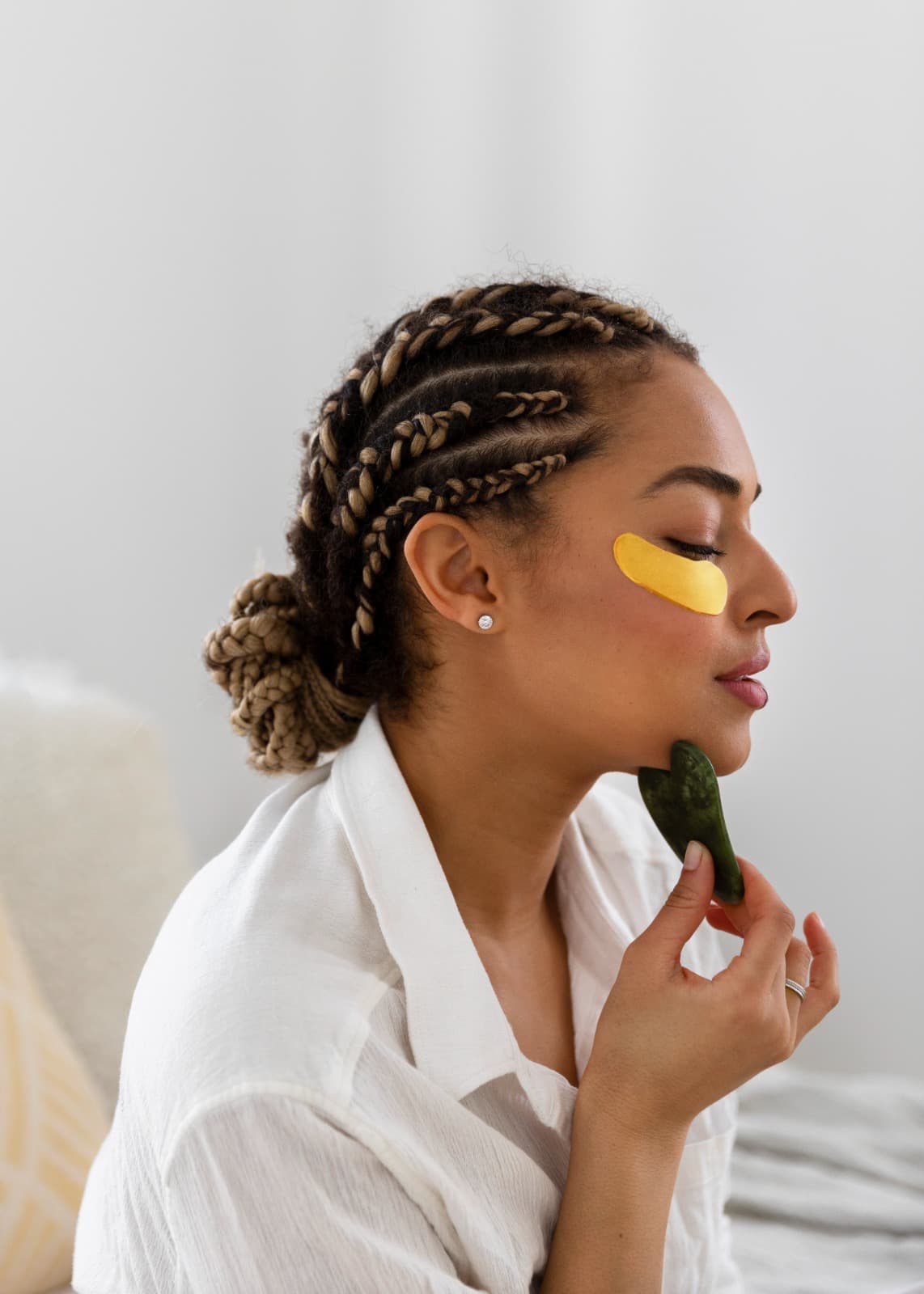 Woman using a green gua sha stone during her skin care routine