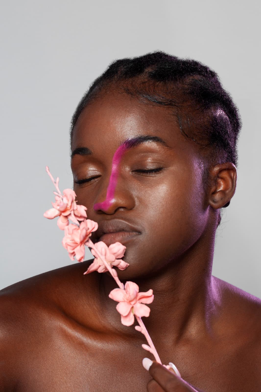 Woman holding a pink blossom beside her face